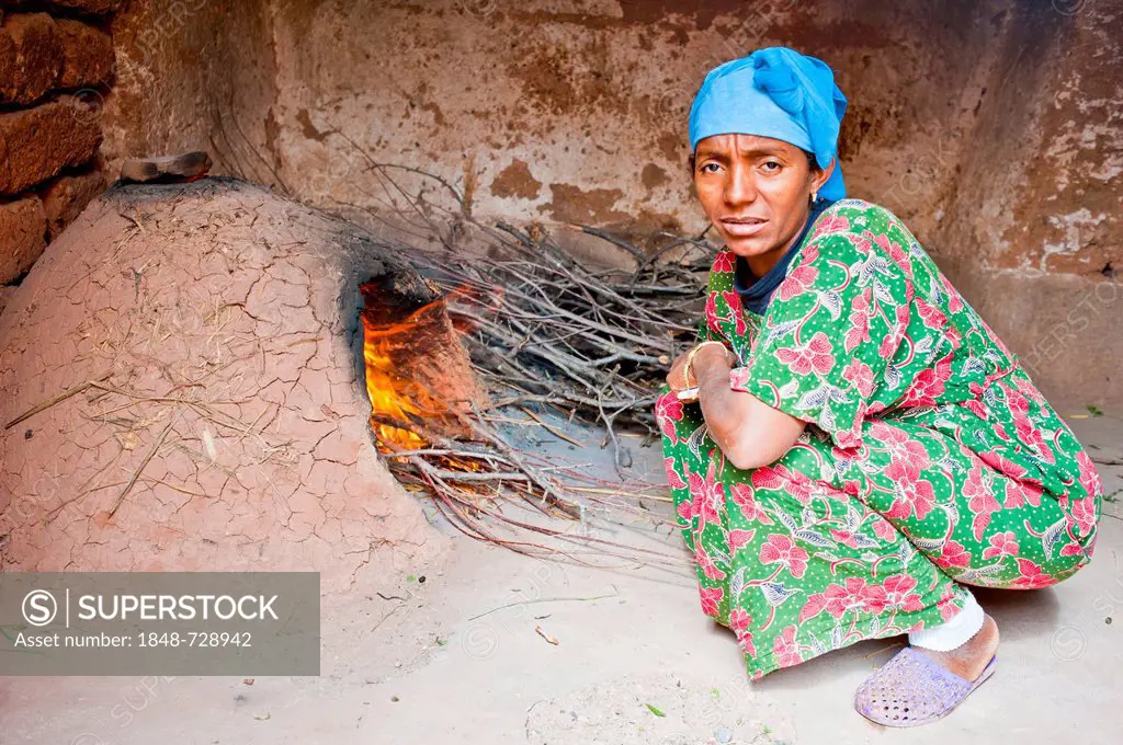 Woman with a blue kerchief, Berber woman, making a fire in a clay oven, southern Morocco, Morocco, Africa