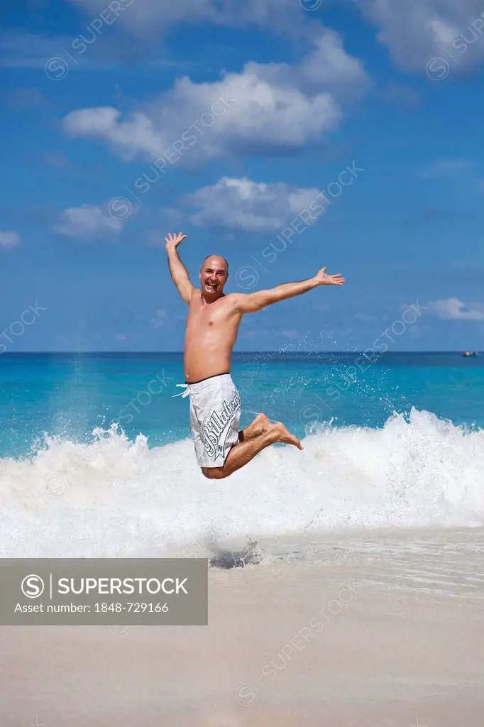 Man, 45 years, leaping into the air with joy on the beach of Anse Intendance, Southern Mahe, Mahe Island, Seychelles, Africa, Indian Ocean