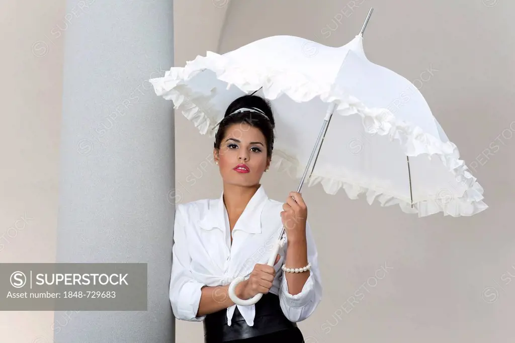 Young woman with an updo hairstyle holding a white umbrella and wearing a white shirt
