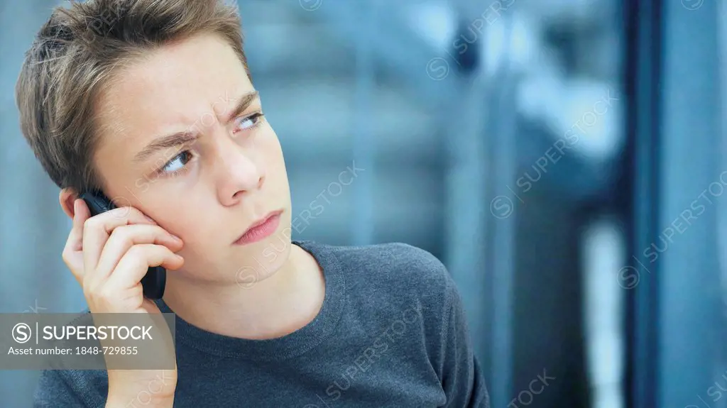 Portrait, boy, teenager looking serious while talking on a mobile phone
