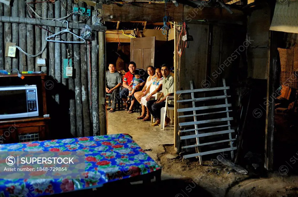 Family of a couple that works in the tourism industry, people sitting in a humble wooden hut at night, on the outskirts of Cancun, Yucatan Peninsula, ...