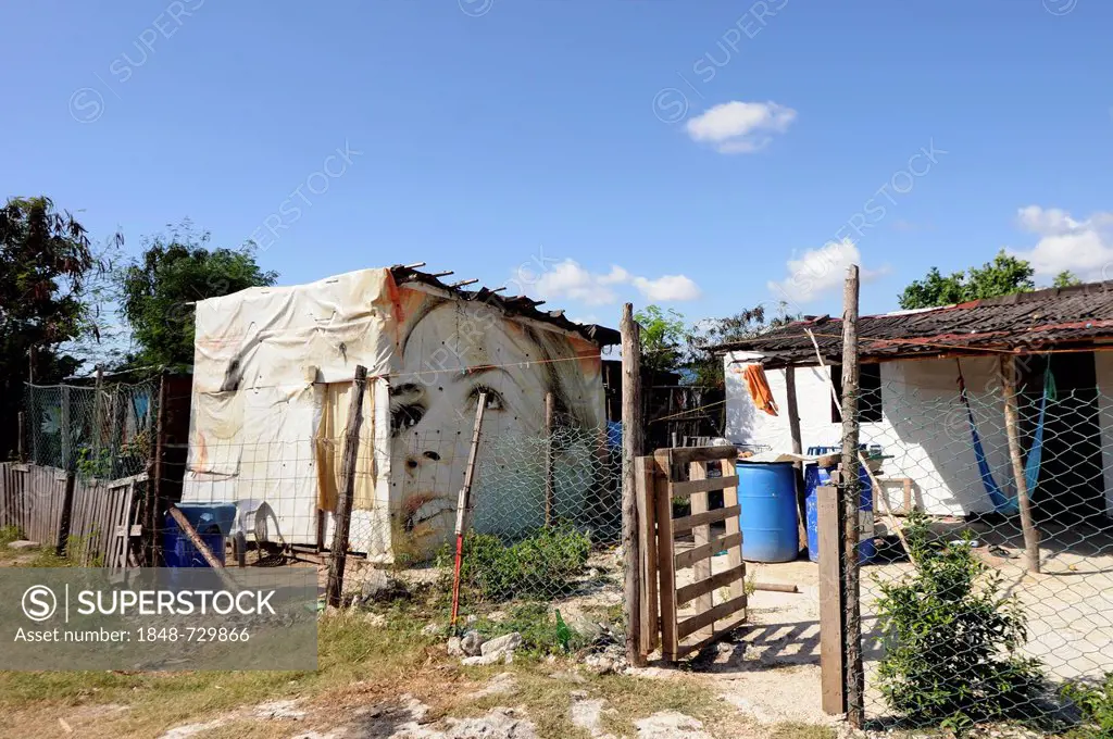 Billboard with the face of a female model serves as an outer wall of a humble cottage in a slum, Cancun, Yucatan Peninsula, Quintana Roo, Mexico, Lati...