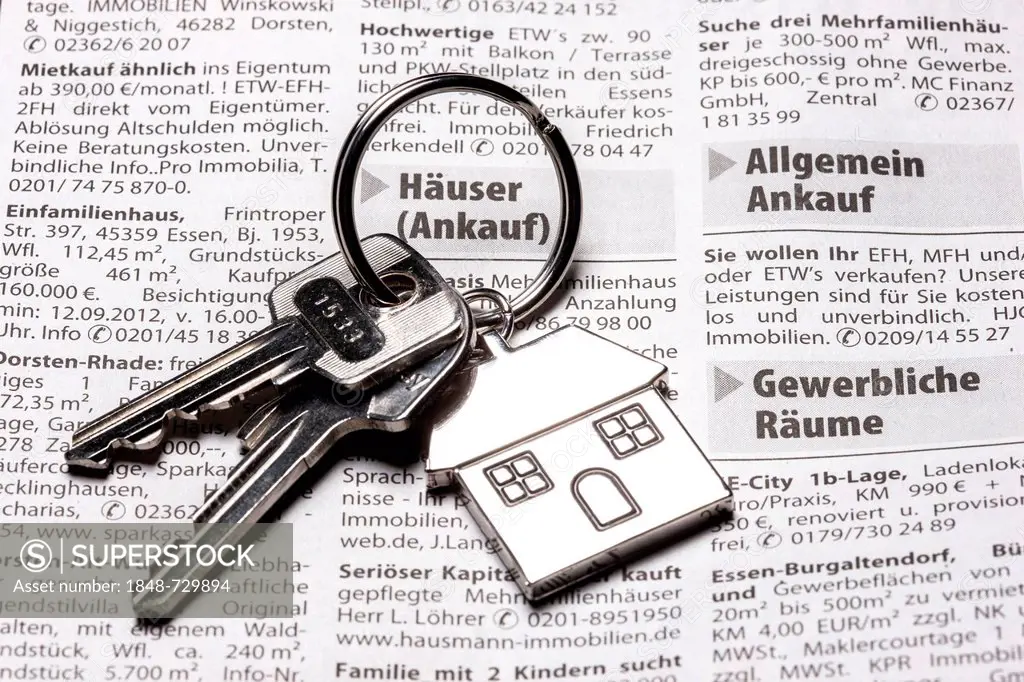 Two keys with a metal key tag shaped like a house lying on the real estate page of a German daily newspaper, symbolic image for home, real estate, hou...