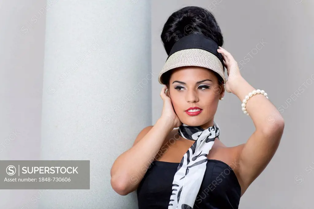 Young woman with an updo hairstyle posing in front of a column, portrait