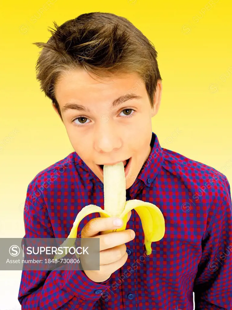 Portrait, boy, teenager biting a banana