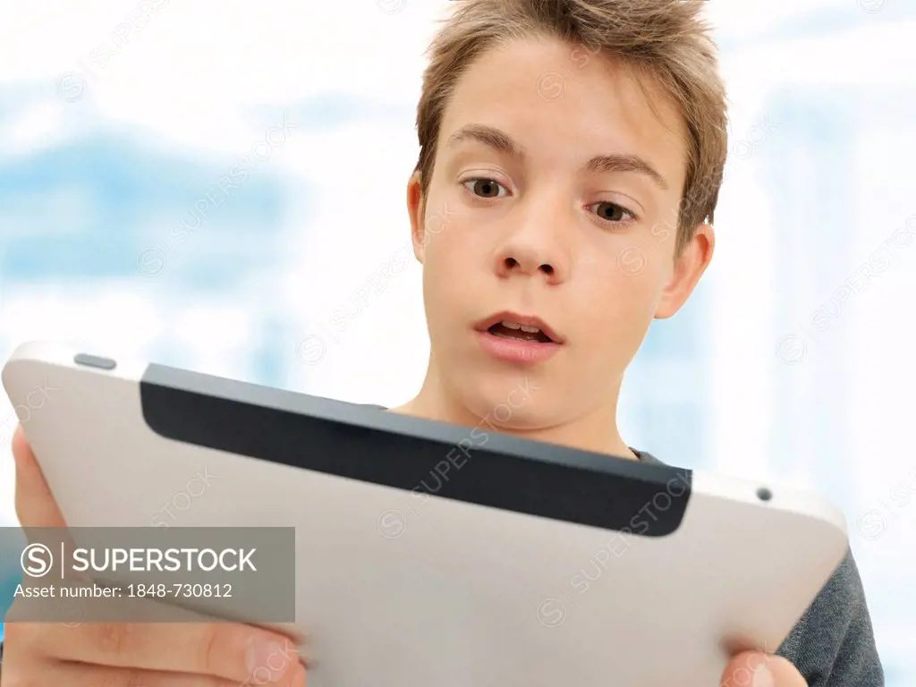 Portrait, schoolboy, teenager looking surprised at an iPad