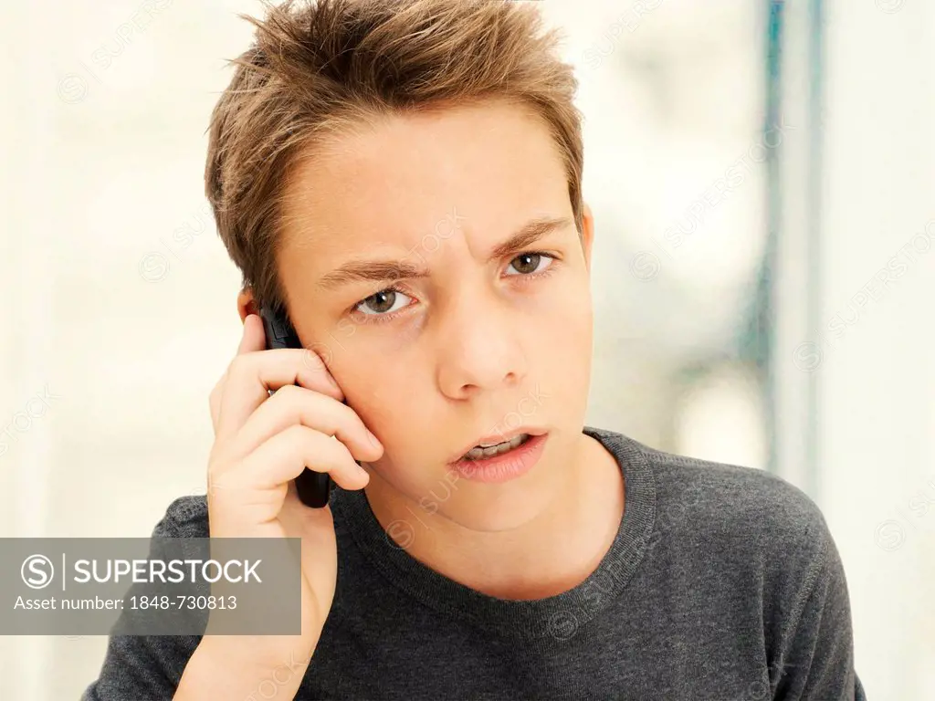 Portrait, boy, teenager looking angry while talking on a mobile phone