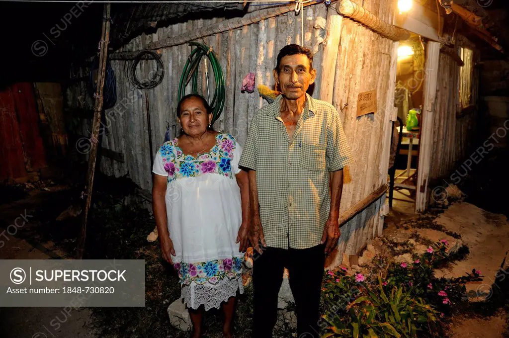 A couple working in the tourism industry standing in front of their humble wooden hut on the outskirts of Cancun, Yucatan Peninsula, Quintana Roo, Mex...