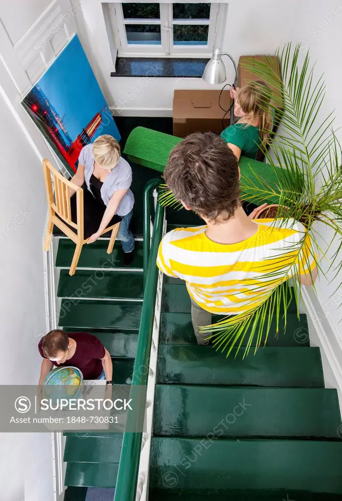 Private house move, friends helping, carrying boxes and furniture down a staircase