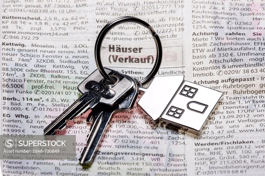 Two keys with a metal key tag shaped like a house lying on the real estate page of a German daily newspaper, symbolic image for home, real estate, hou...