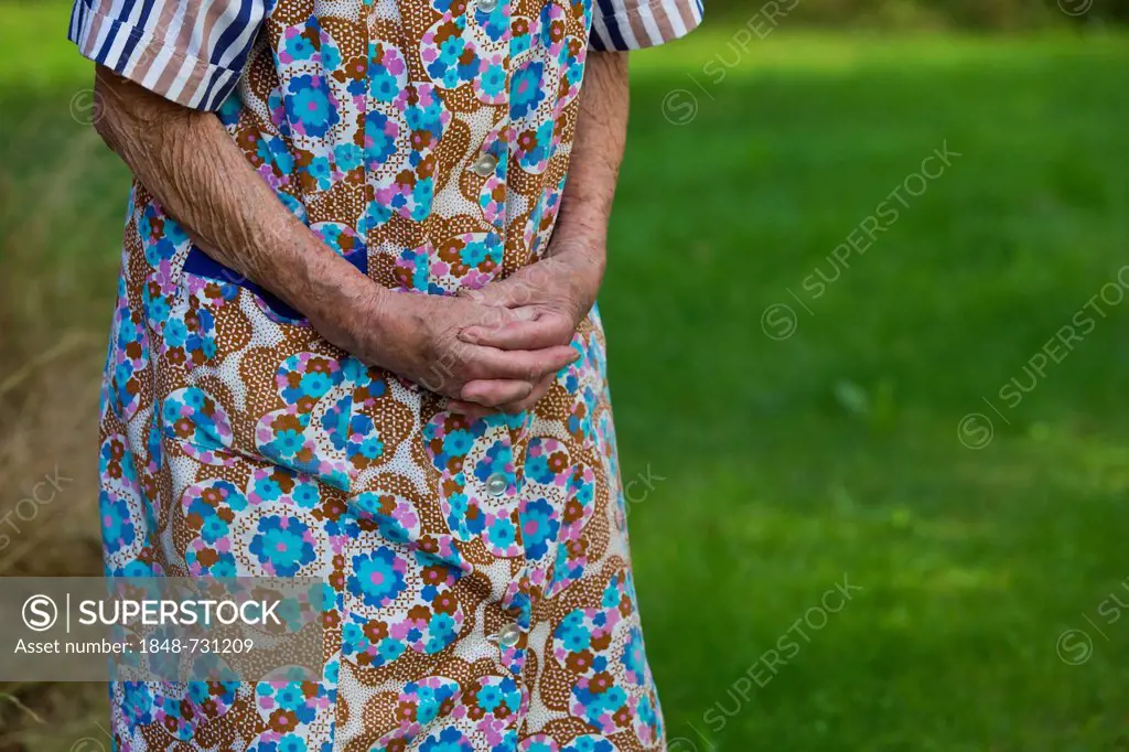 Elderly woman with her hands folded in front of her