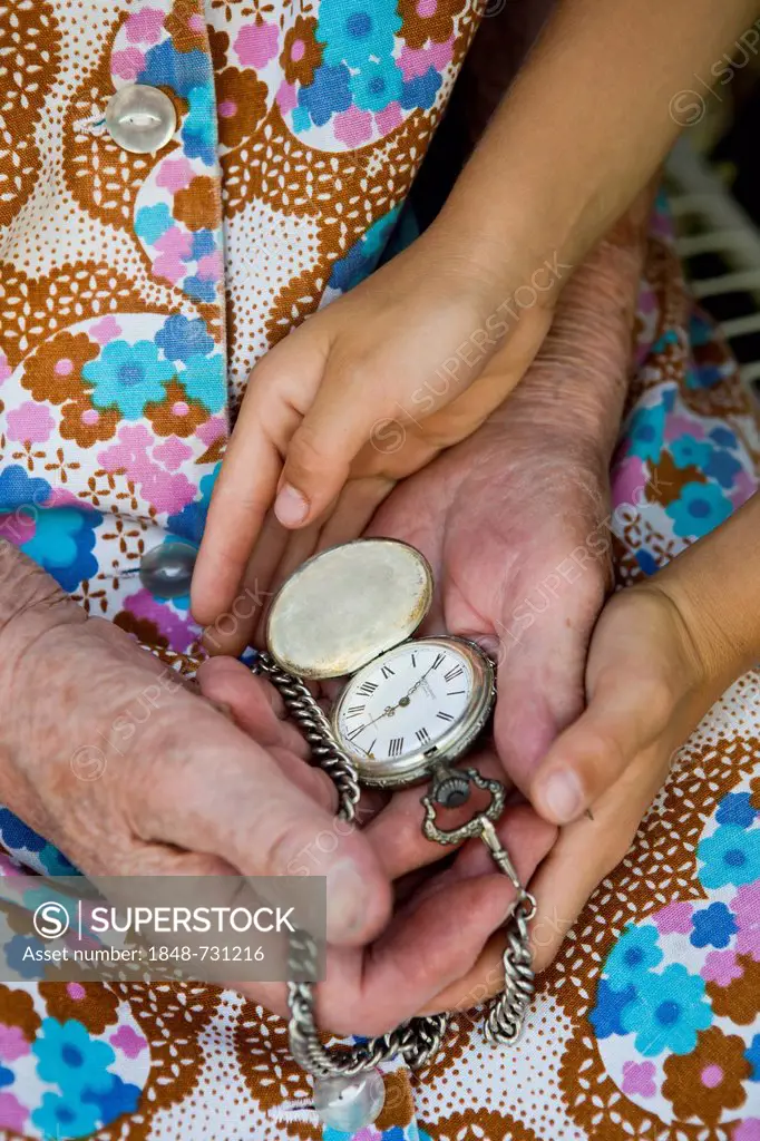Elderly woman and a child holding an old pocket watch in their hands