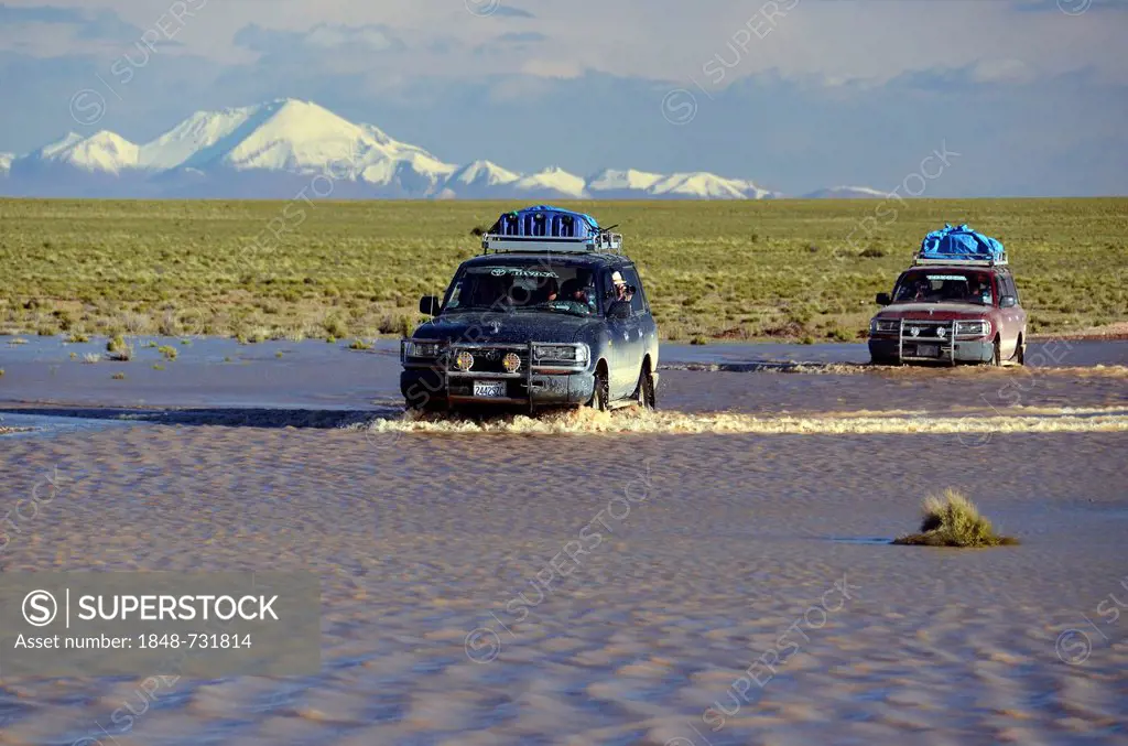 Tourists traveling through the wild landscape of the Altiplano high plateau in off-road vehicles, Bolivia, South America
