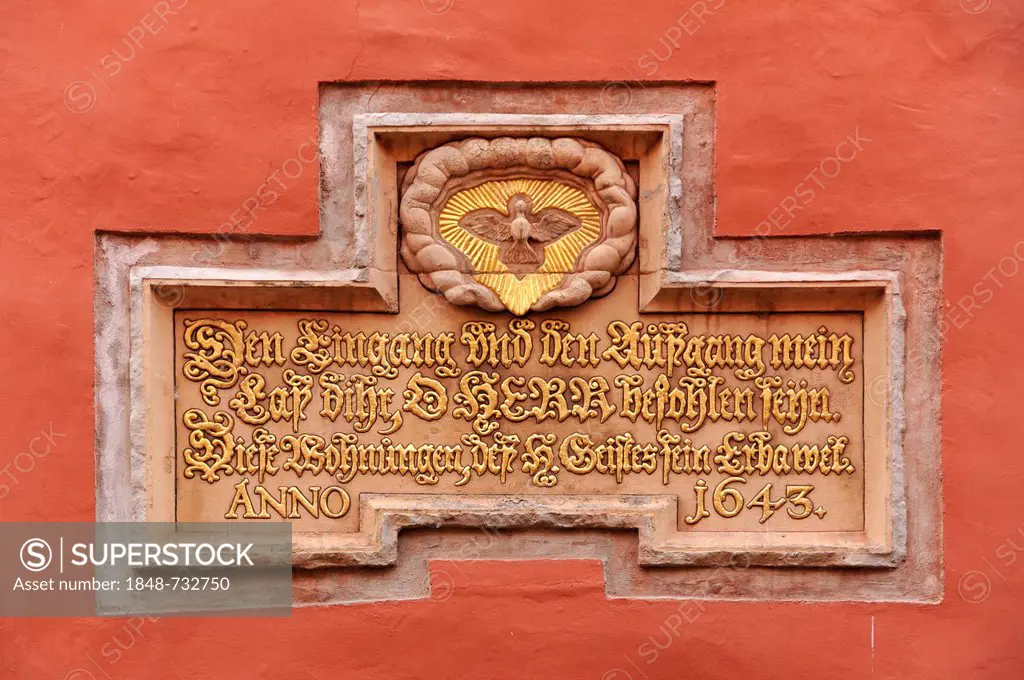 Gold-plated Christian quote and a dove as a symbol of the Holy Spirit above the doorway to the Heilgeist-Wohnungen apartments, Heilgeistkirche church,...