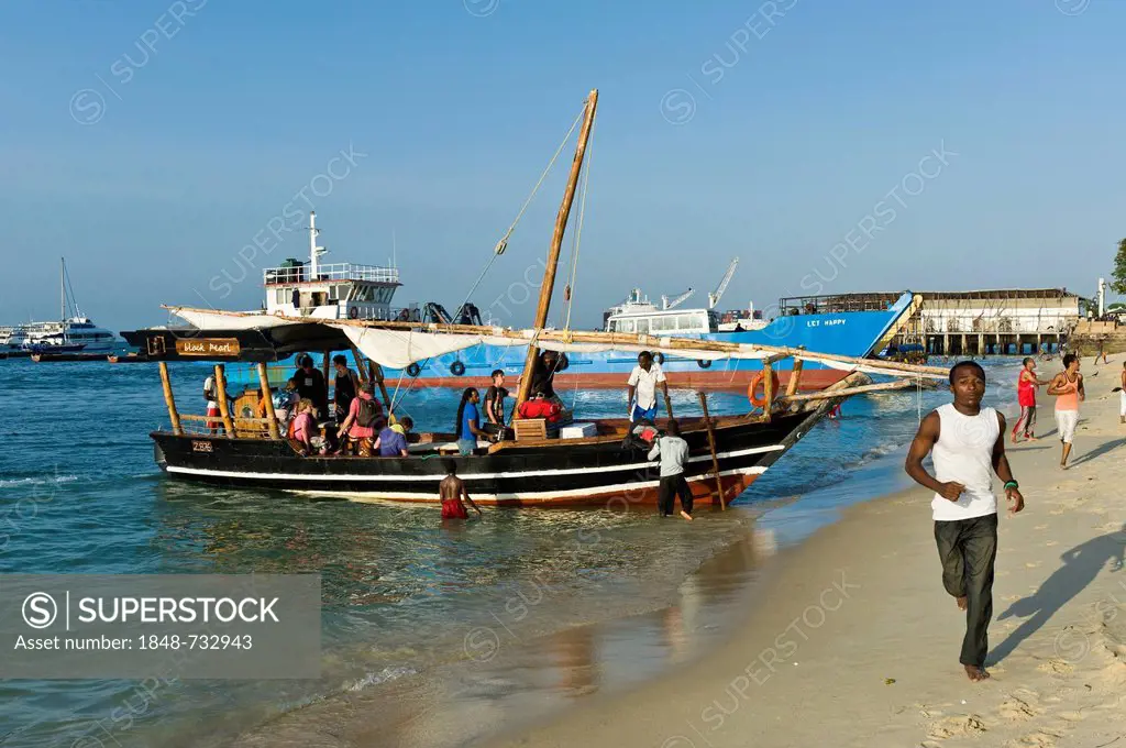 Tourists boarding an excursion boat, harbour of Stone Town, Zanzibar, Tanzania, Africa