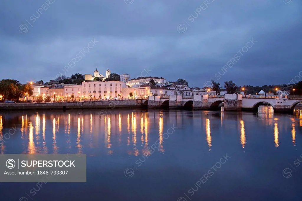 The lights of the old town and the Roman bridge are reflected in the Gilao river, Tavira, Algarve, Portugal, Europe