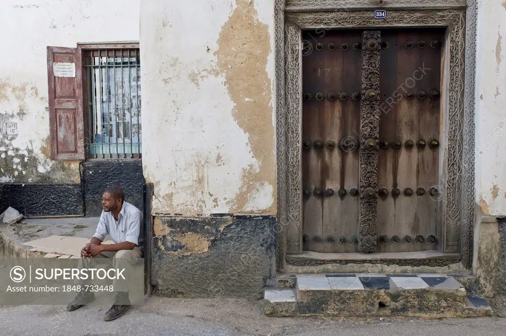 Man and an old ornate Arabic door in Stone Town, Zanzibar, Tanzania, Africa