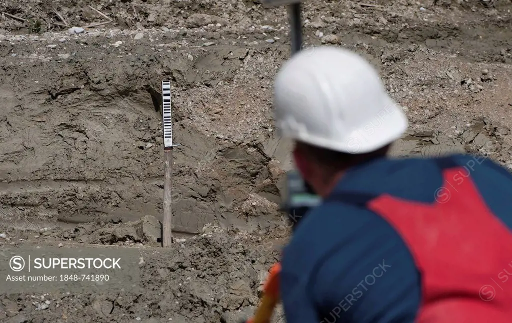 A structural engineer is taking measurements of a possible soil dropping during a building site load test, at a construction site in Fridolfing, Bavar...