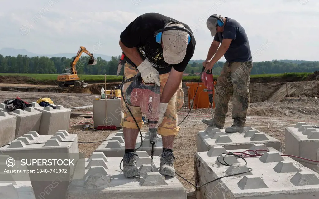 Construction workers drilling holes into concrete blocks during a building site load test at a construction site in Fridolfing, Bavaria, Germany, Euro...