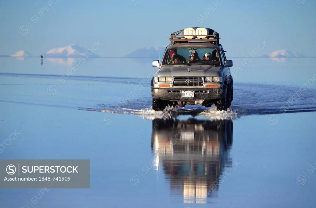 Jeep with tourists travelling on the Salar de Uyuni with reflections, near Uyuni, Altiplano, Bolivia, South America