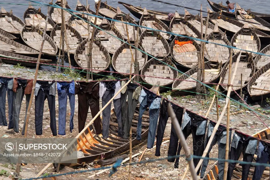 Jeans hanging to dry on clotheslines in front of boats on the bank of the Buriganga River, Dhaka, Bangladesh, South Asia, Asia