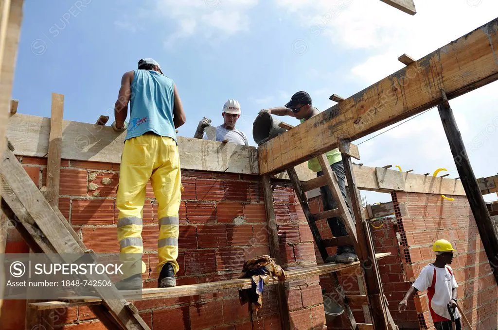 People from the slums, favelas, working together on a construction site of the Esperanca housing co-operative, each family helping out on the project ...