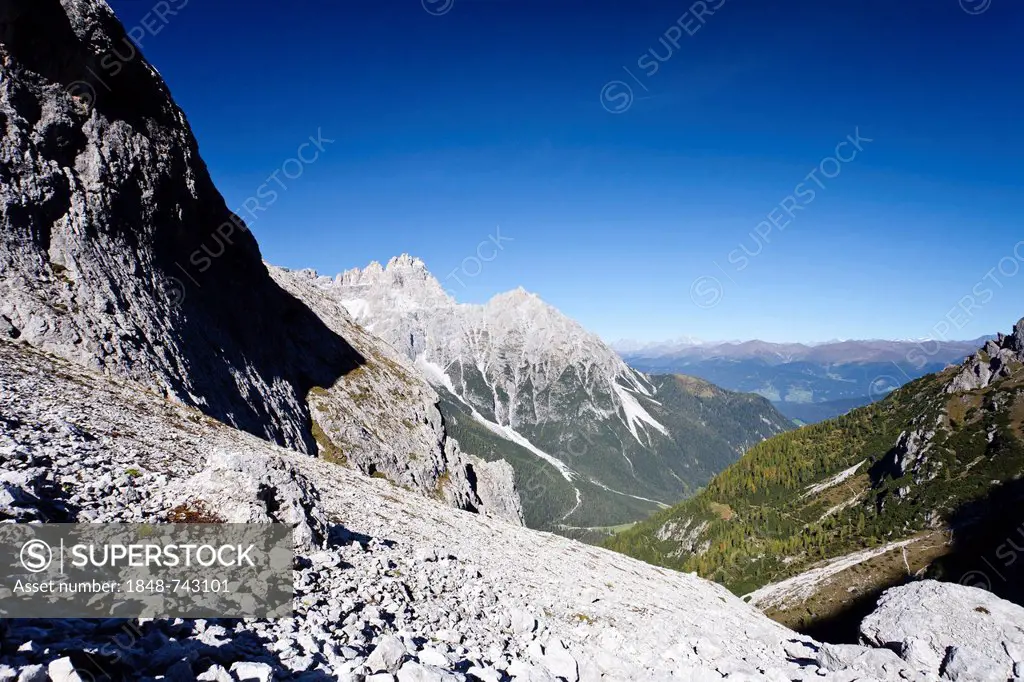 Hiker during the ascent to Alpinisteig Mountain through the Fischlein Valley above the Talschlusshuette hut, with Dreischusterspitze Mountain at the r...