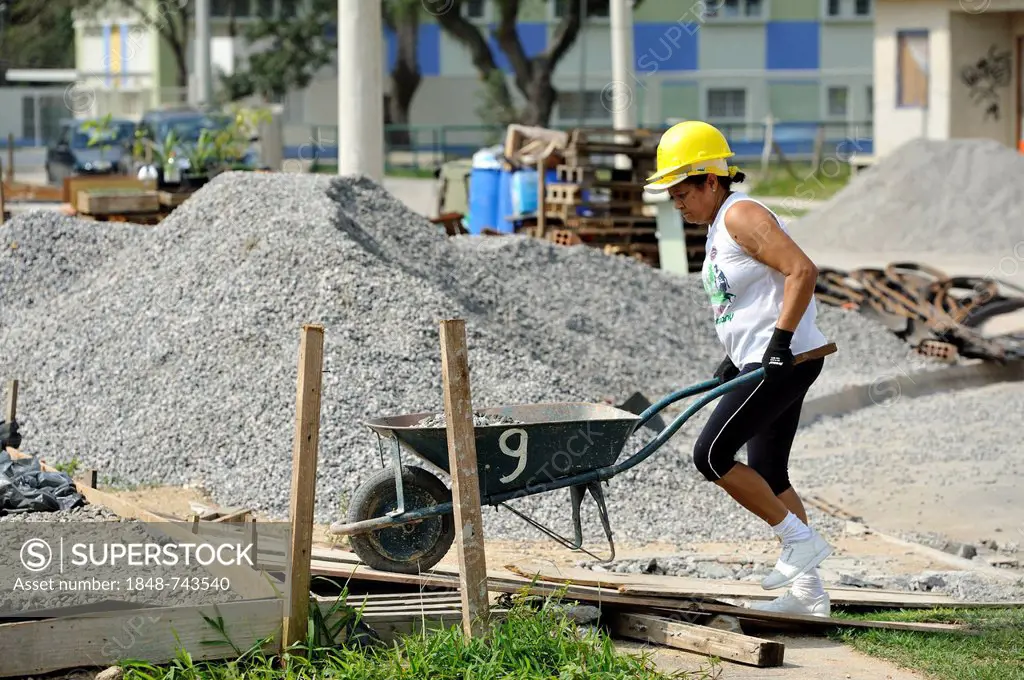 Woman pushing a wheelbarrow on a building site of the Esperanca housing co-operative, each family helping out on the project and committing to small m...