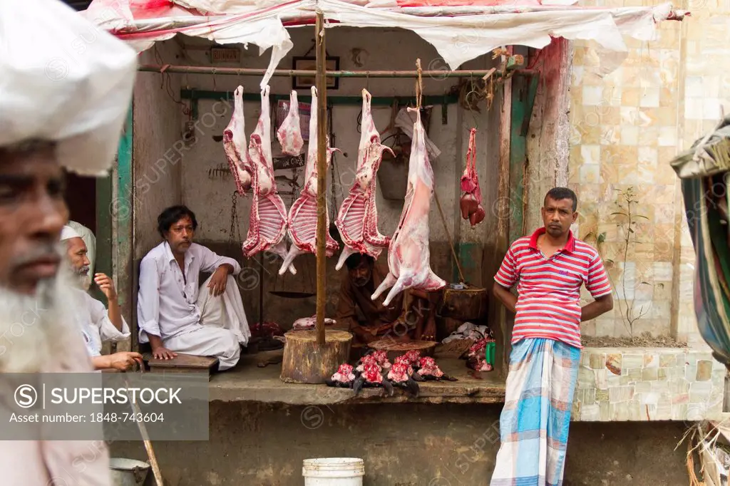 Roadside slaughterhouse, skinned animals hanging from beams, raw meat underneath, butcher waiting for customers, Dhaka, Bangladesh, South Asia