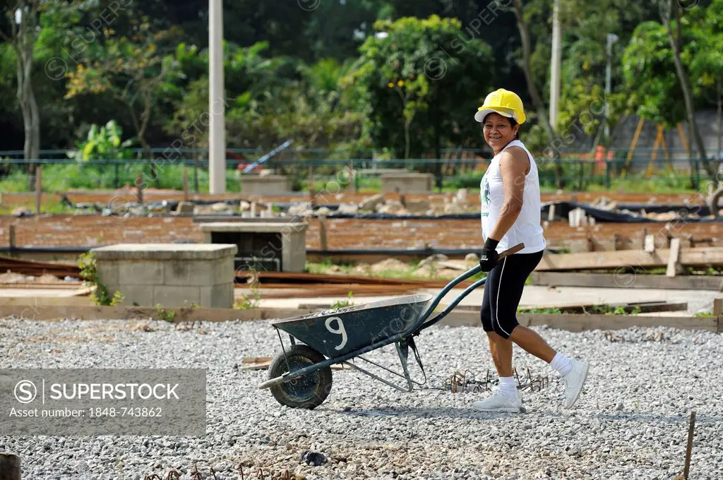 Woman pushing a wheelbarrow on a building site of the Esperanca housing co-operative, each family helping out on the project and committing to small m...