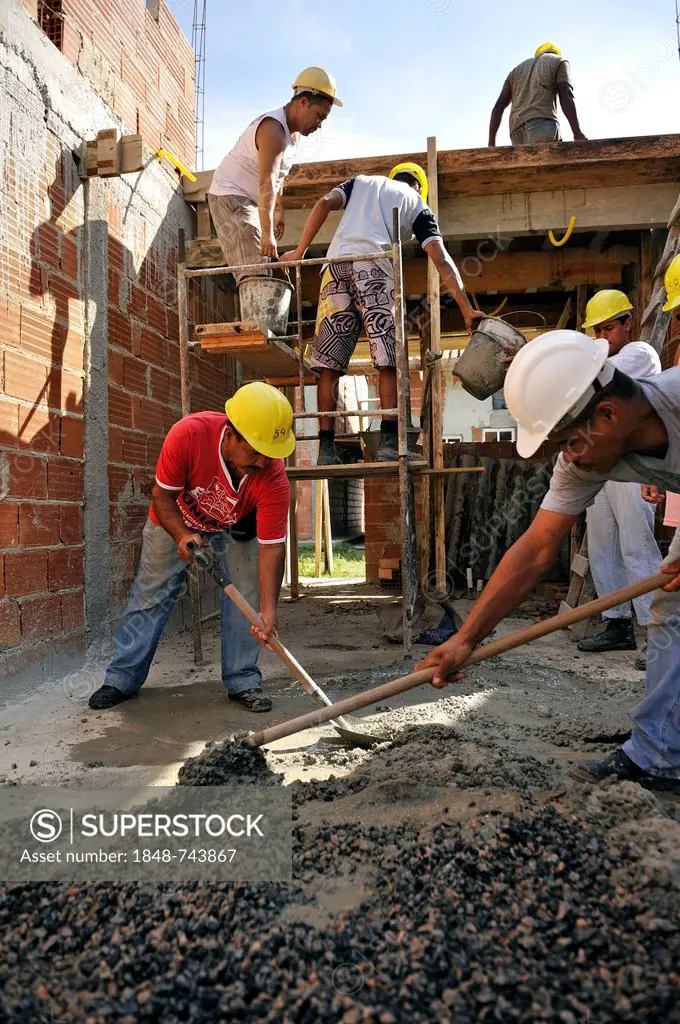 Mixing of concrete, people from the slums, favelas, working on a building site of the Esperanca housing co-operative, each family helping out on the p...