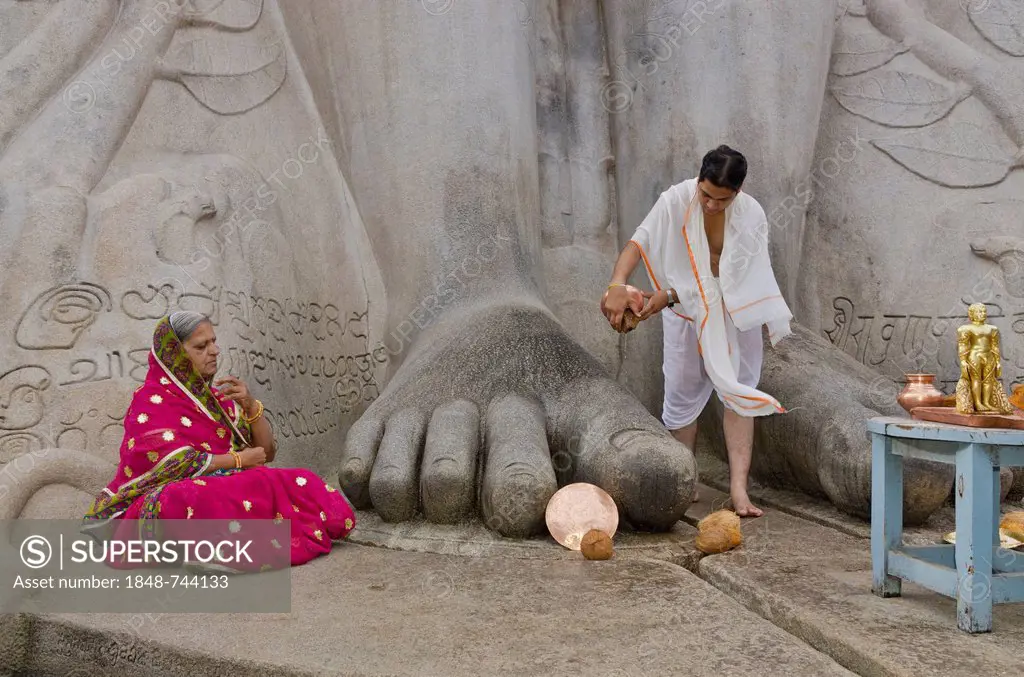 Priest is pouring water on the feet of the gigantic statue of Gomateshwara in Sravanabelagola, pilgrim meditating, Sravanabelagola, India, Asia