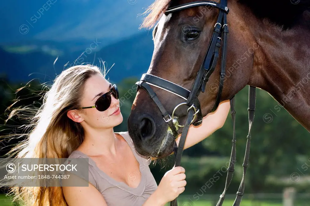 Young woman wearing sunglasses cuddling with a horse, Hanoverian, bay, North Tyrol, Austria, Europe