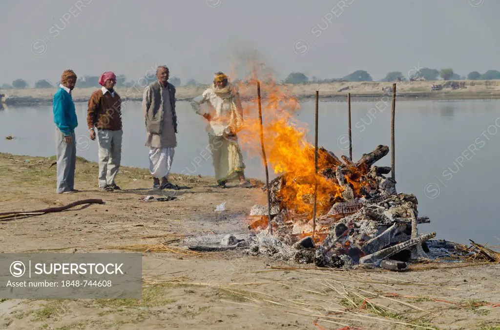 Group of people watching the cremation ceremony of a family member on the banks of river Yamuna, Vrindavan, India, Asia