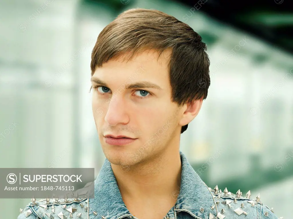 Young man with a serious face wearing a studded denim jacket, portrait