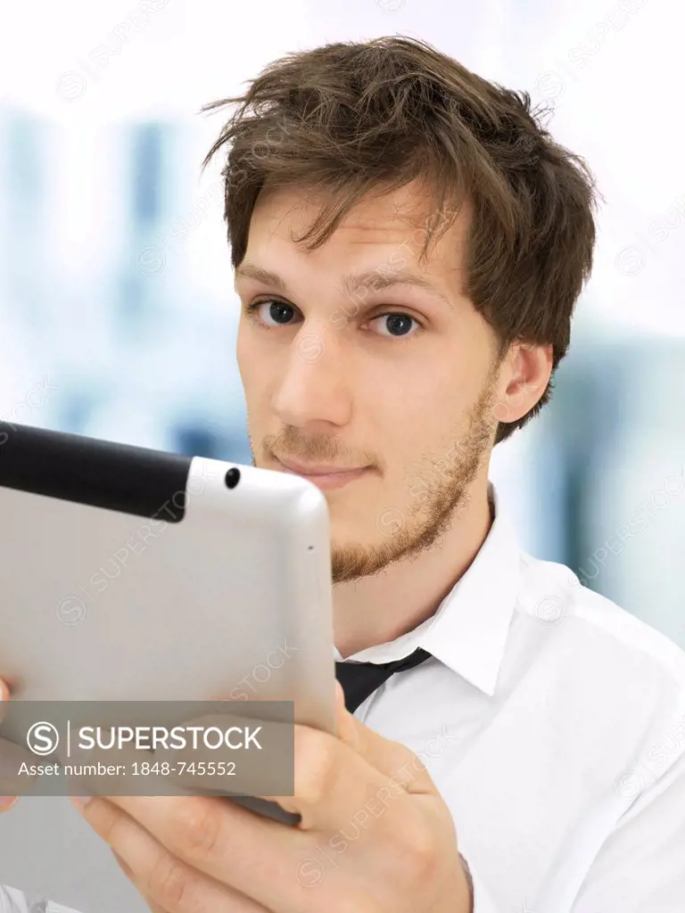 Portrait of a businessman holding an iPad, looking serious, concentrating