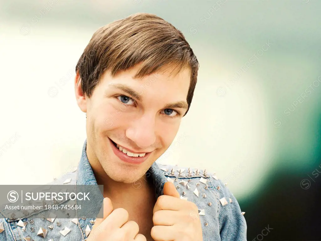 Smiling young man wearing a studded denim jacket, portrait