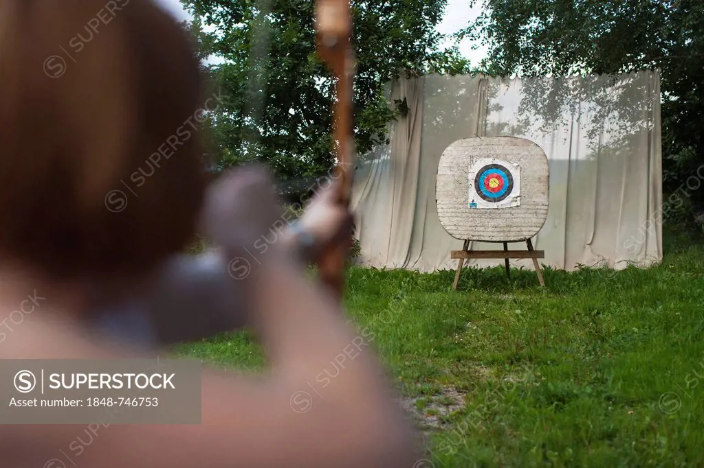 Archery, woman aiming bow and arrow at a target, Germany, Europe