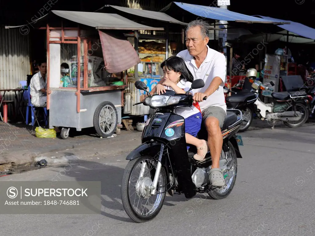Man with a child on a motor scooter, Phnom Penh, Cambodia, Southeast Asia, Asia