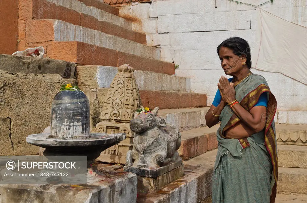 Woman praying to a Shiva Lingam, at the ghats of Varanasi, India, Asia