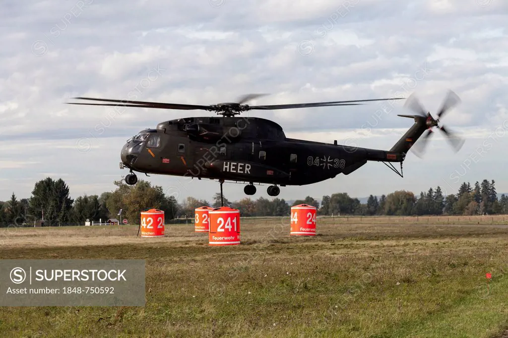Firefighters hanging a 5000-liter water tank under a CH-53 helicopter of the German armed forces, during an exercise, Laupheim, Baden-Wuerttemberg, Ge...