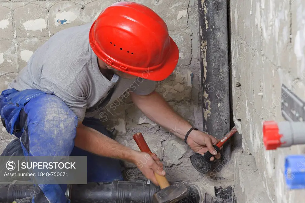 An electrician, systems mechanic for sanitary engineering, heating and air conditioning, installing a sewer pipe, driving a slot for a sewer pipe, ref...