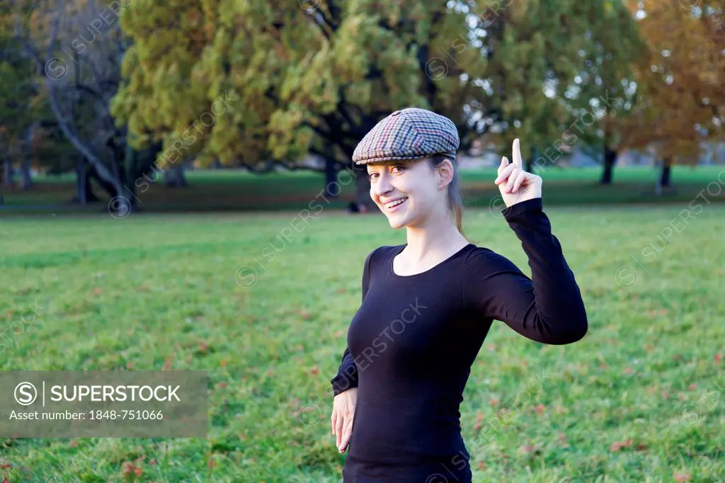Young woman with cap and pointing index finger