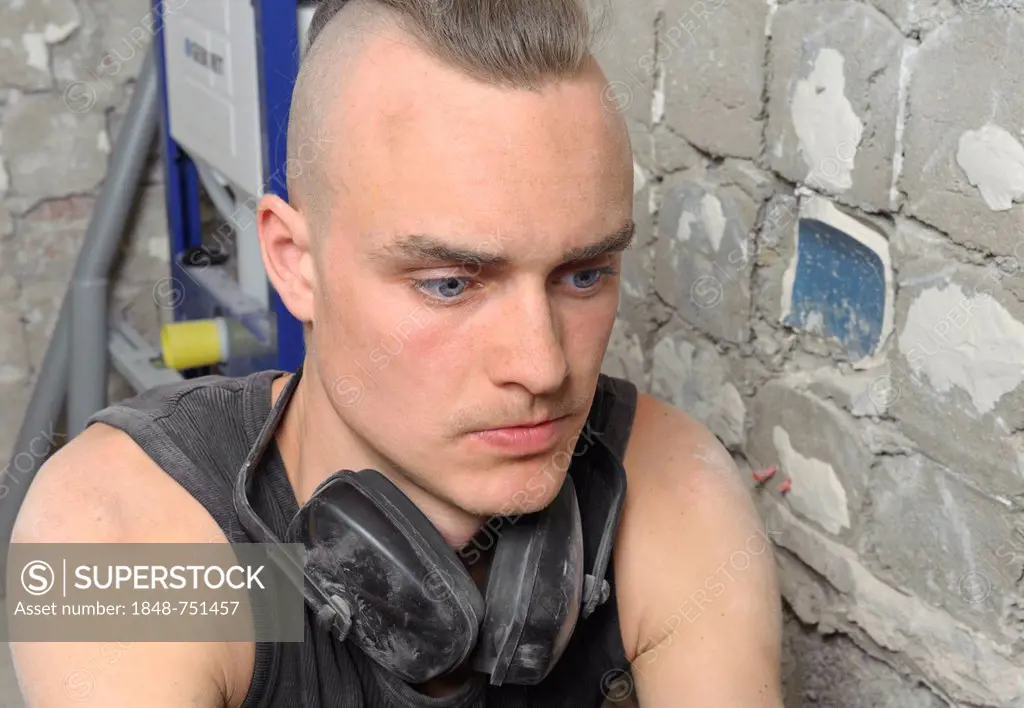 A young man with partly shaved head looking at the done work on a construction site, refurbishment, Baden-Wuerttemberg, Germany, Europe