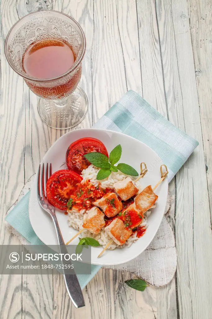 Turkey skewers on rice with tomato sauce and grilled tomatoes