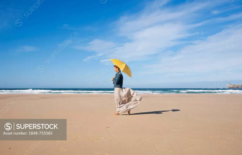 Woman walking with an umbrella on a beach