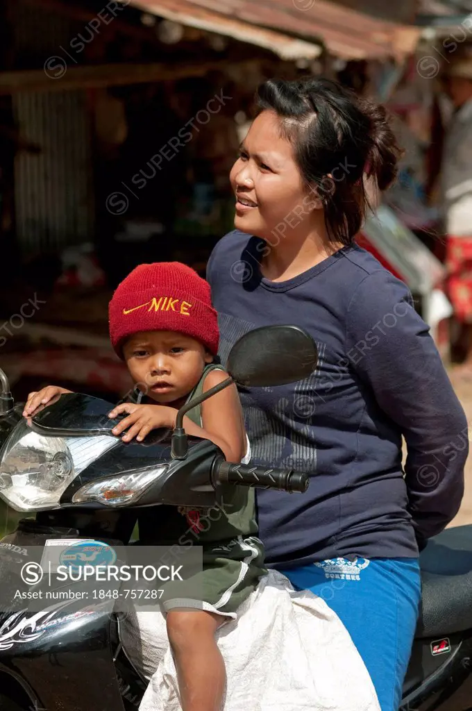Woman and child with Nike hat on a motorcycle, Battambang, Cambodia, Southeast Asia