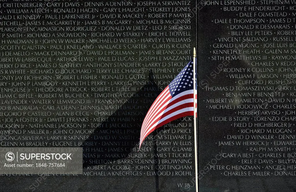 U.S. Flag flying in front of the Vietnam Veterans Memorial Wall, national memorial with the names of the fallen U.S. soldiers in the Vietnam War, Wash...