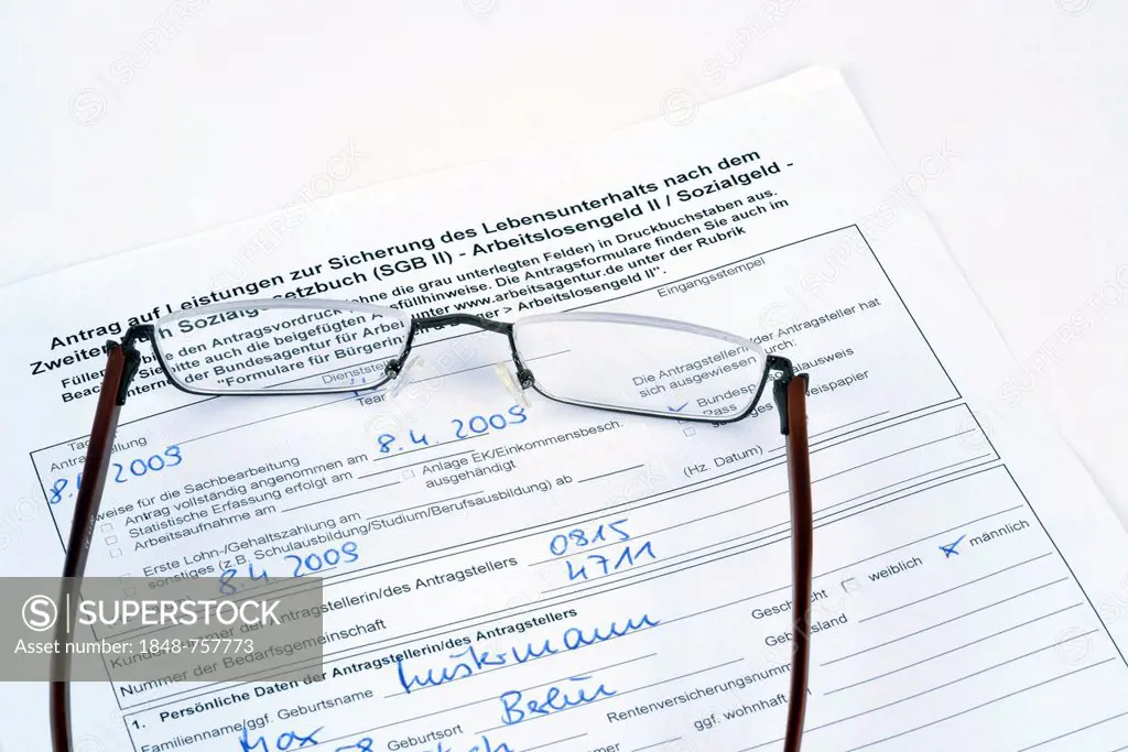 Reading glasses lying on a German application for an unemployment benefit, Hartz IV