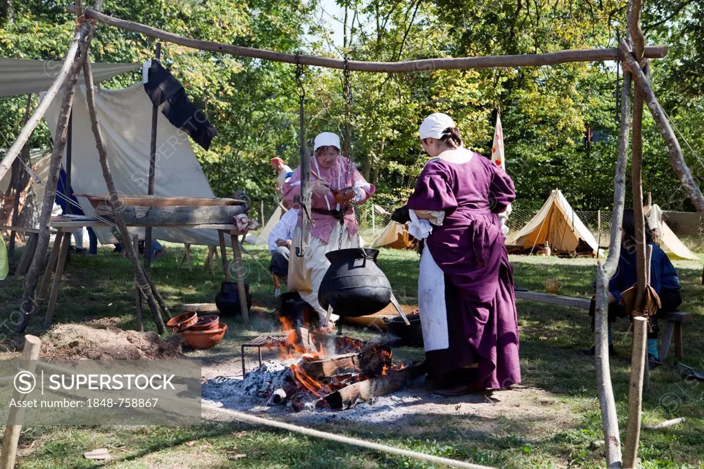 Women with a cooking pot over a campfire, live role-playing or ReenLarpment, historical reconstruction by a reenactment group, in front of the Musée d...